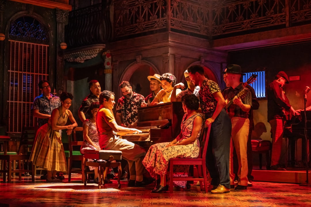 Cast members gather around the piano in The Broadway Company of Buena Vista Social Club. Photo By Matthew Murphy