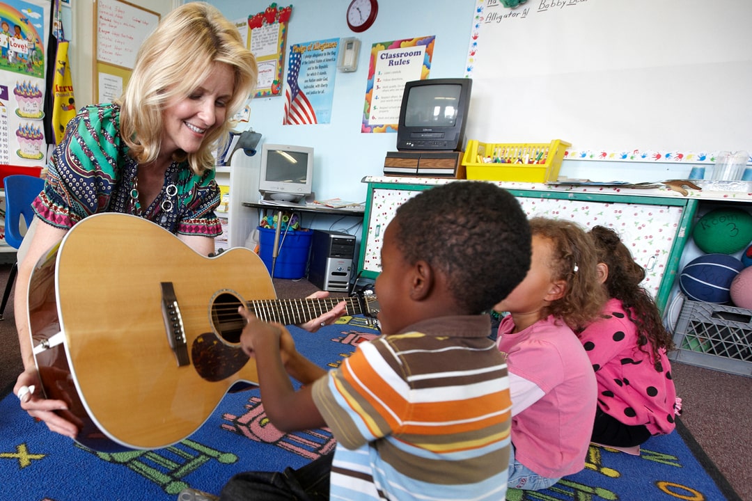 A Smith Center teaching artist showing students a guitar in their classroom