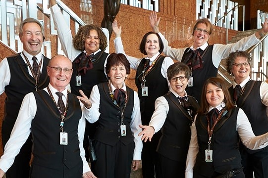 An image of ushers smiling and posing with their hands in the air